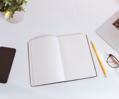 White work table with notes, smartphone and laptop